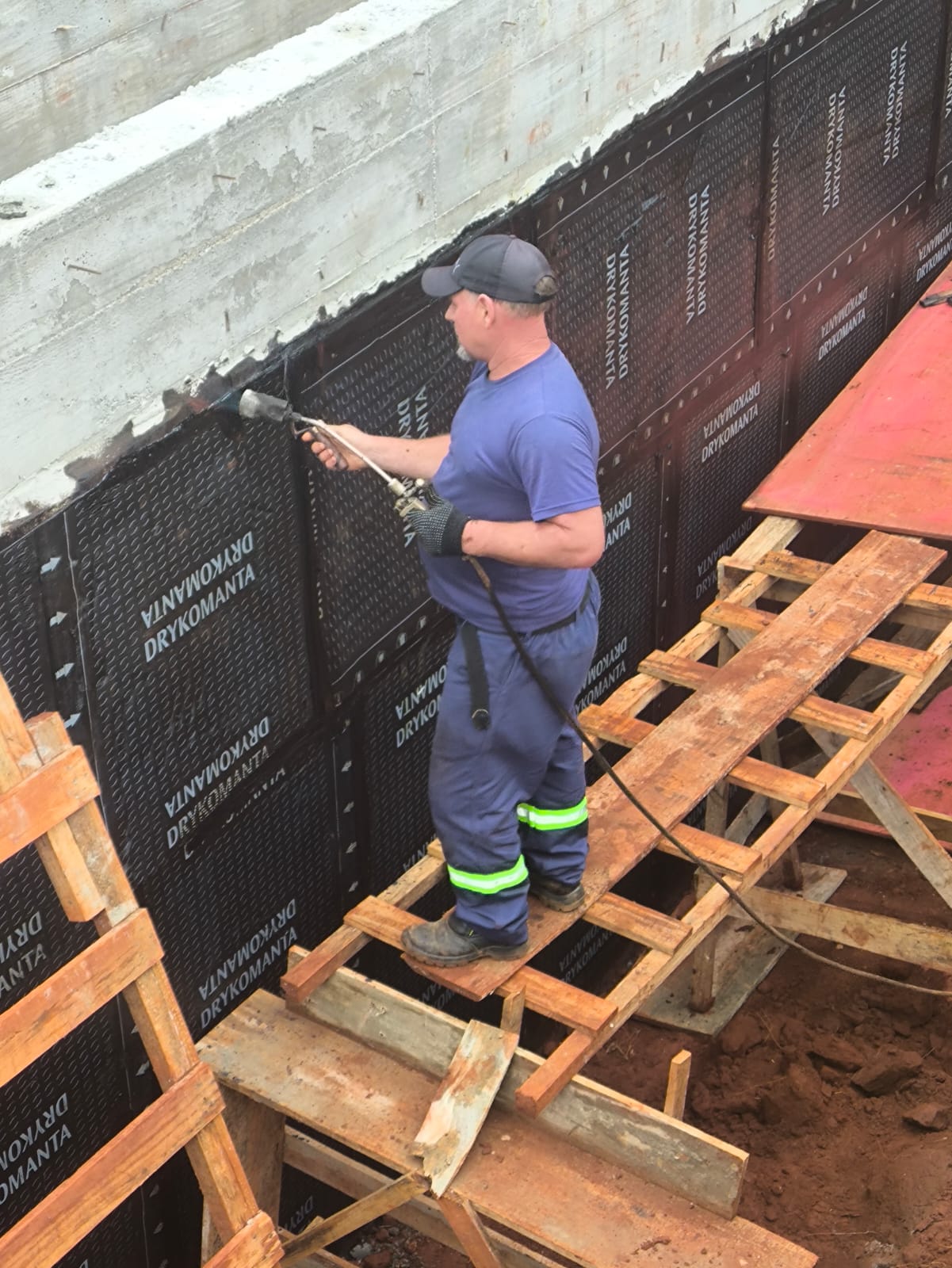 Trabalhador aplicando produto de impermeabilização em obra